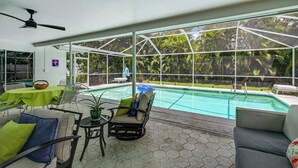 A covered outdoor area with a pool, seating, and a view of a tropical garden. - Lanai, Pool Access! Naples Studio Near Beach (Naples)