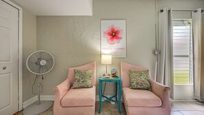 A room with two pink armchairs, a teal side table, a fan, and a window with a curtain. - Lanai, Pool Access! Naples Studio Near Beach (Naples)