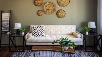 A living room with a beige sofa, two side tables with lamps, a patterned rug, and decorative wall art.