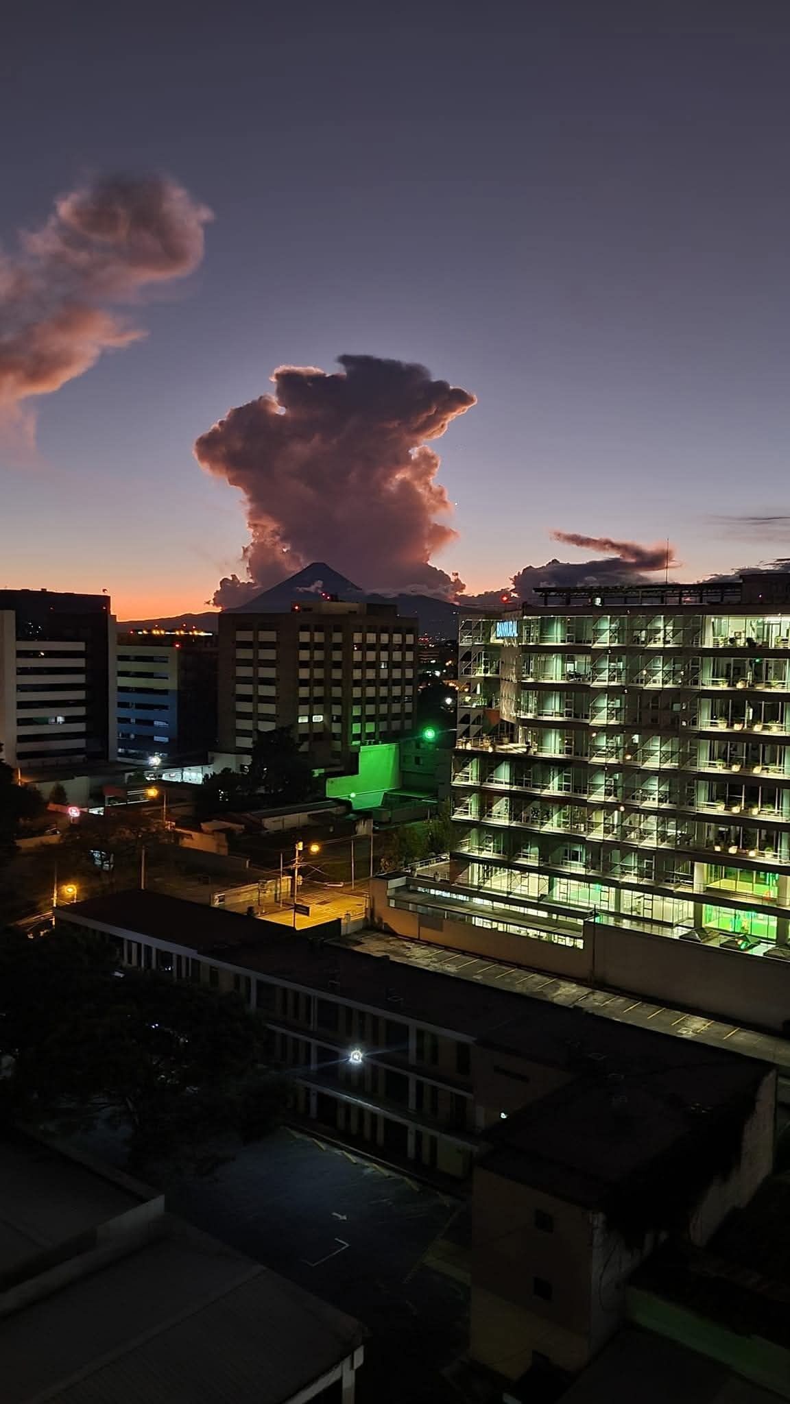Un edificio de varios pisos con ventanas iluminadas y una estructura iluminada en verde al frente.