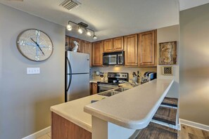 A modern kitchen with wooden cabinets, a stainless steel refrigerator, a microwave, and a built-in oven. - Gulf Views & Beach Access! 2 PCB Condos w/ Pool! (Panama City Beach)