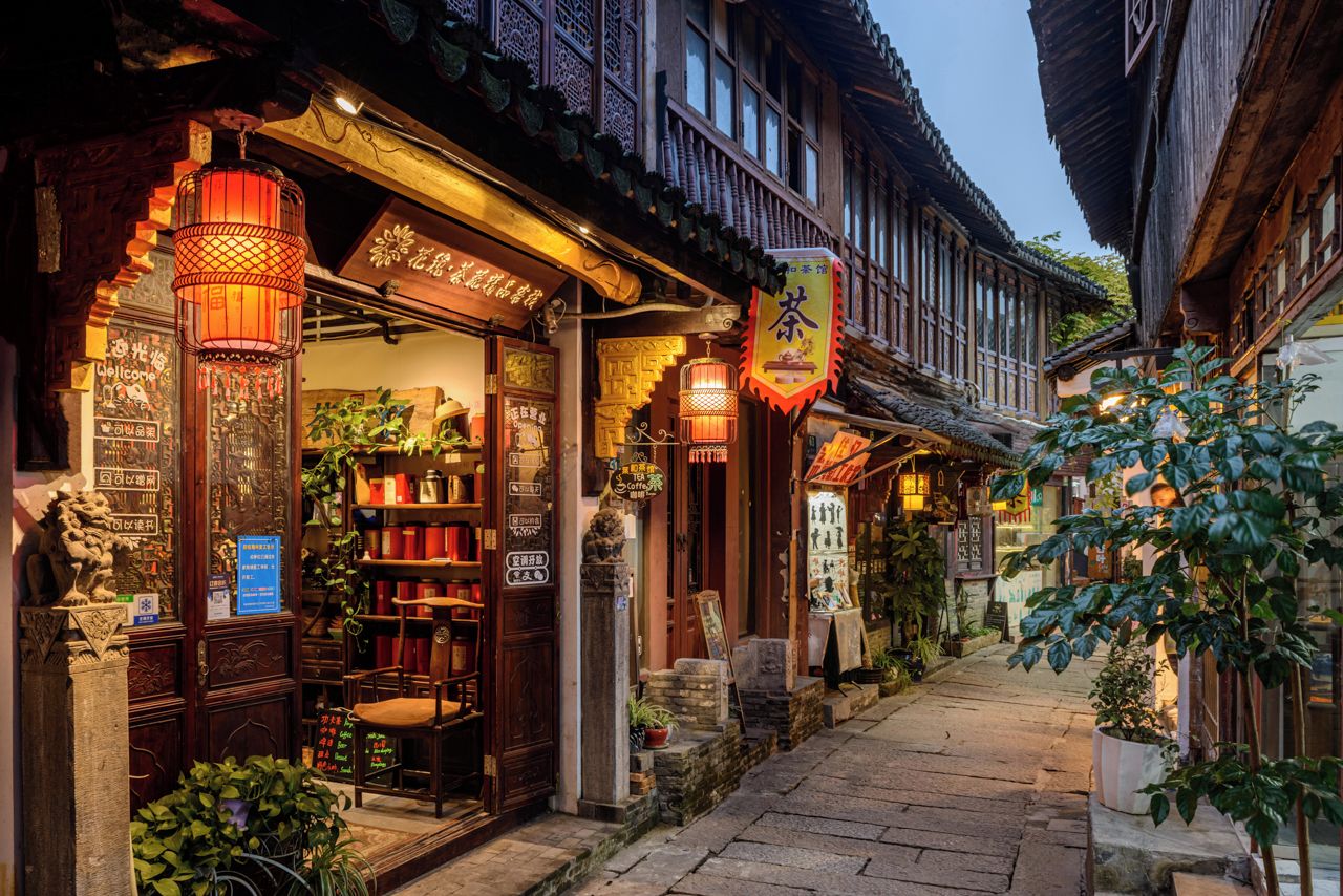 A traditional street with wooden buildings, lanterns, and signage in a foreign language.