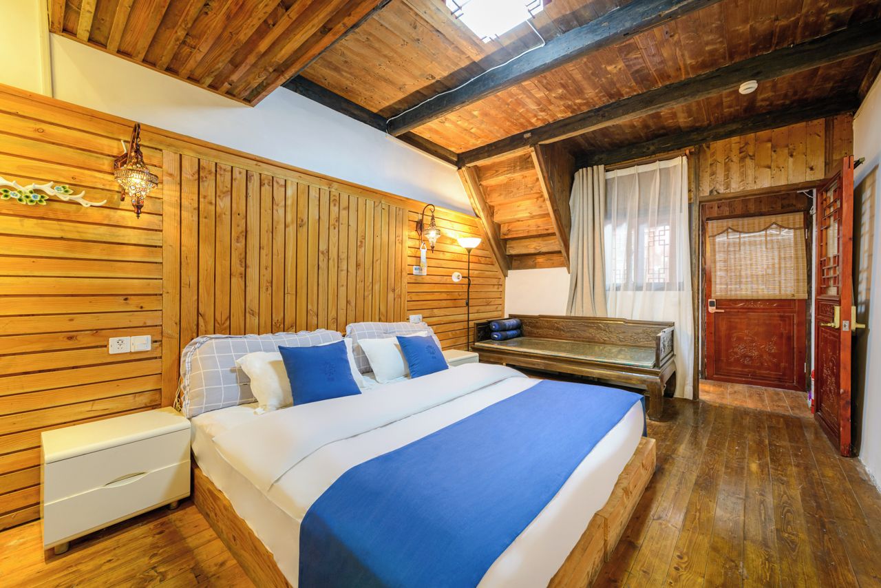 Una habitación con paneles de madera, una cama, una mesita de noche y un banco.