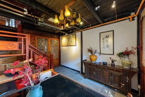 A traditional interior with a wooden staircase, a dining area with a table and chairs, and a decorative wall with framed artwork. - Zhujiajiao Chayuan Boutique Hotel (Shanghai)