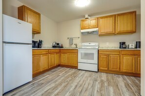 A kitchen with wooden cabinets, a white refrigerator, a stove, and a microwave. - Cañon City Apt 3 Mi to Arkansas Riverwalk Trail (Cañon City)