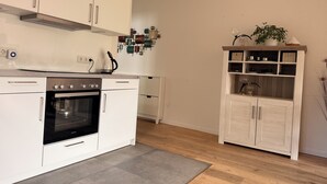 A modern kitchen with white cabinetry, a built-in oven, and a coffee maker.