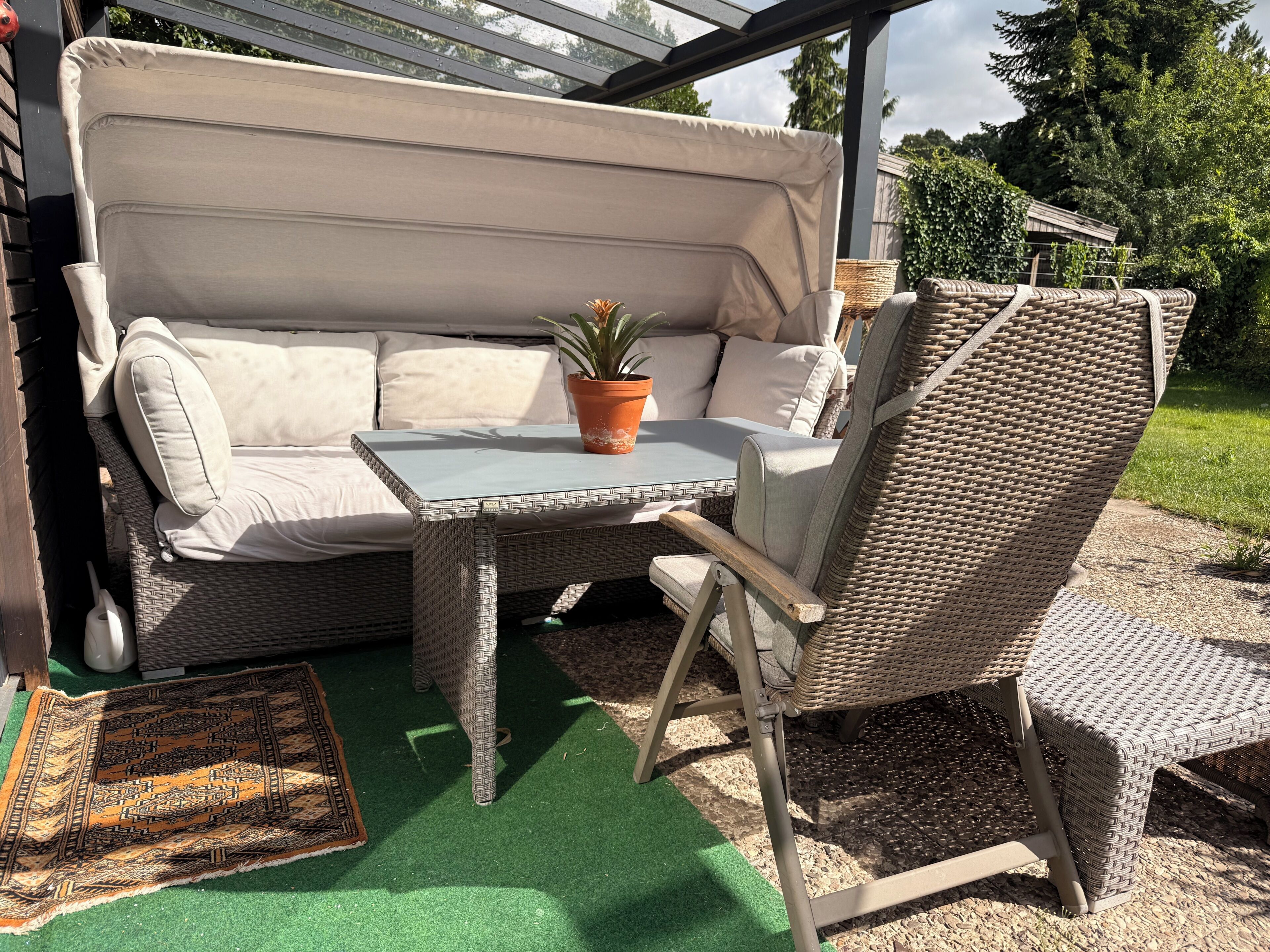 Un área de estar al aire libre con un sofá, una mesa y una silla.