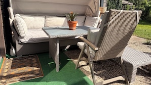 An outdoor seating area with a sofa, a table, and a chair.