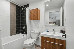 A modern bathroom with a bathtub, toilet, and vanity. - 1 Bedroom/1 Bathroom Suite (Montreal)