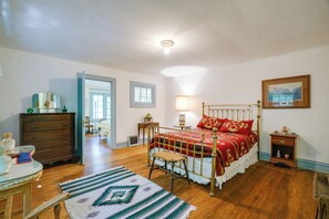 A bedroom with a bed, dresser, lamp, and a painting on the wall.