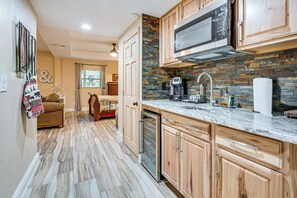 A modern kitchen with wooden cabinets, a built-in microwave, and a stone backsplash. - Family Friendly! Scenic Murphy Escape w/ Fire Pit (Murphy)