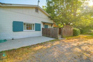 A single-story building with a white exterior and blue shutters, a gravel driveway, and a wooden fence. - Easy Access to UAFS & Downtown! Cozy Apt w/ Patio (Fort Smith)