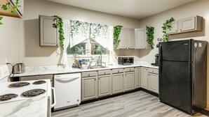 A kitchen with white cabinets, a black refrigerator, a microwave, and a stove.