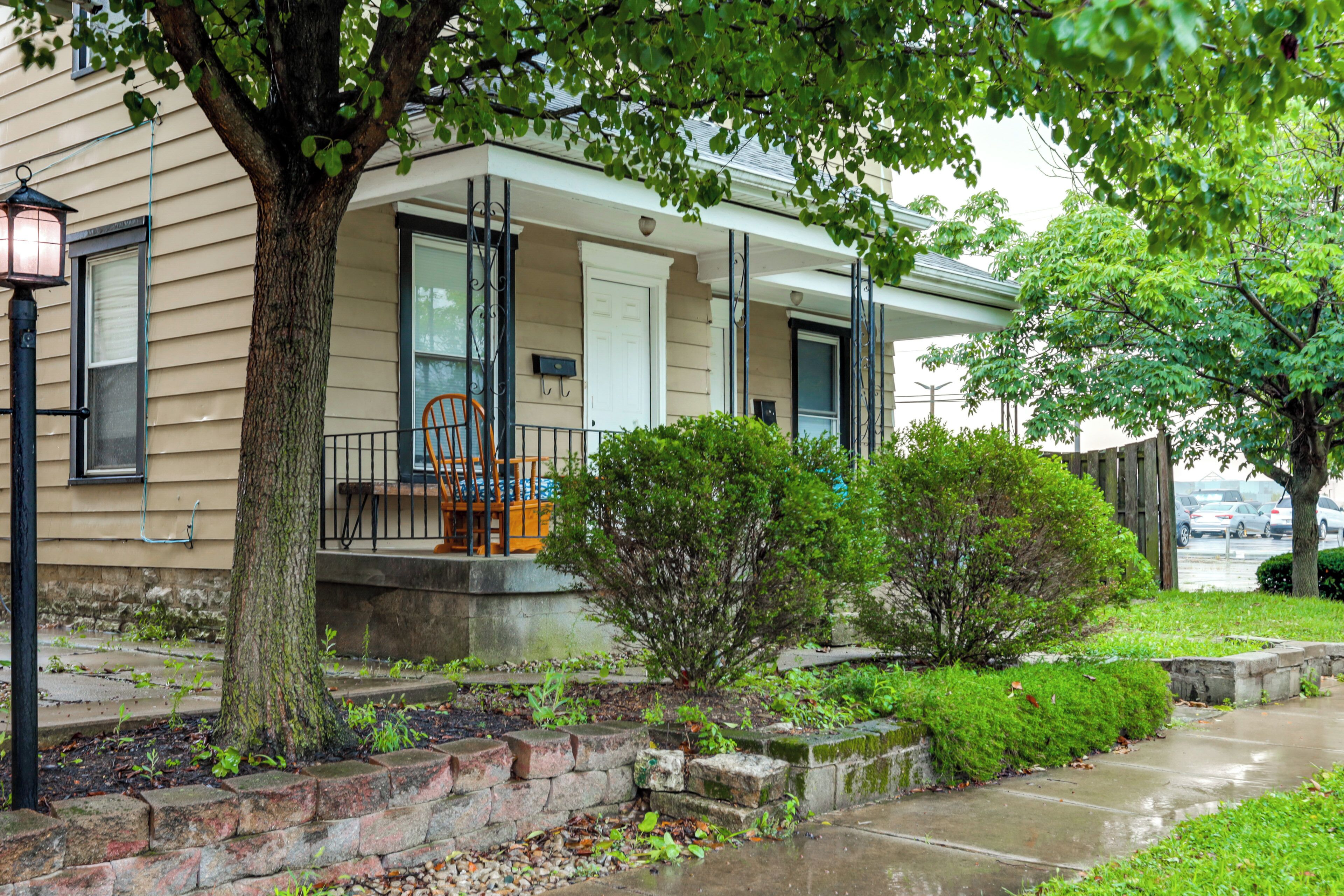 A residential house with a front porch, a small garden, and a visible mailbox.