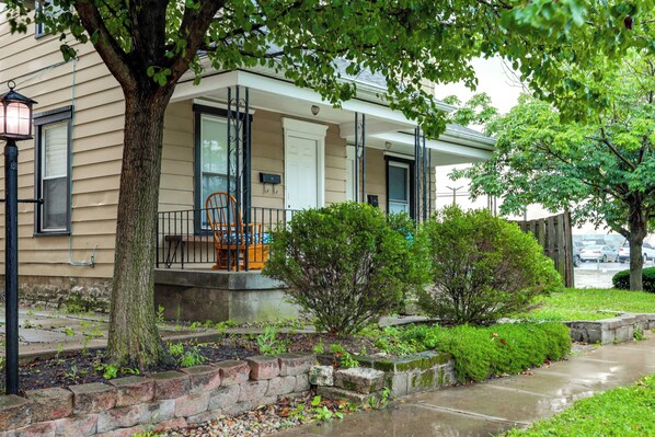 A residential house with a porch, a small tree, and a well-maintained lawn.