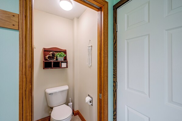 A bathroom with a toilet, a wooden shelf with a plant, and a towel rack. - Family-Friendly Goshen Home Near Amish Country (Goshen)