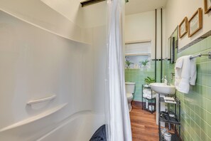 A bathroom with a bathtub, shower, sink, and a towel rack. - Hike, Golf & Explore! Family Gem in Dtwn Bedford (Bedford)