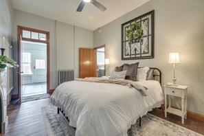 A bedroom with a bed, bedside table, lamp, and a view of the outside. - Hike, Golf & Explore! Family Gem in Dtwn Bedford (Bedford)