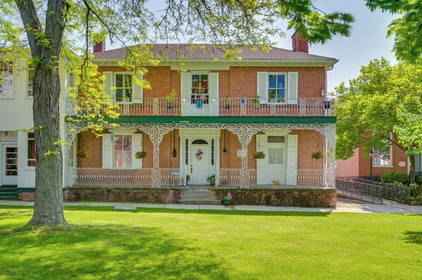 A two-story brick house with a green porch, white railings, and a front door with a wreath. - Hike, Golf & Explore! Family Gem in Dtwn Bedford (Bedford)