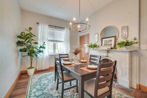 A dining room with a wooden table, chairs, a chandelier, a potted plant, and a fireplace with a sign reading "Pennsylvania". - Hike, Golf & Explore! Family Gem in Dtwn Bedford (Bedford)