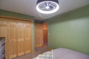 A bedroom with a bed, a wardrobe, and a door leading to another room.