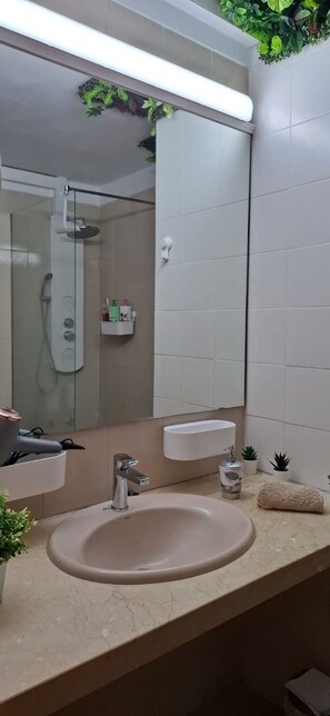 A bathroom with a sink, mirror, and shower. - Amara Apartment in a 3 pool holiday complex with bars and shops near to ocean (Golf del Sur)