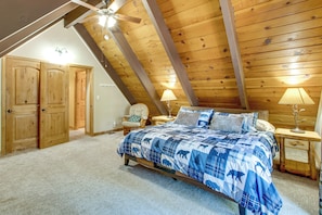 A bedroom with a sloped ceiling, wooden walls, a bed with a blue and white patterned bedspread, two bedside lamps, and a chair. - Minutes to Slopes & Shore! Cozy Cabin w/ Hot Tub (South Lake Tahoe)