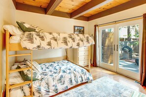 A bunk bed with a patterned bedspread, a wooden dresser, and a sliding glass door leading to an outdoor area. - Minutes to Slopes & Shore! Cozy Cabin w/ Hot Tub (South Lake Tahoe)