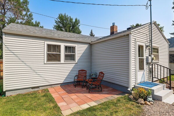 Einbungalow mit einer Terrasse, auf der ein Tisch und zwei Stühle stehen.