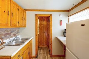 Eine kleine Küche mit Holzschränken, einem Spülbecken und einem Kühlschrank.