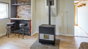 A room with a fireplace, a bar area with stools, and a wooden floor. - Walk to Park & Creek! Spearfish Couple’s Retreat (Spearfish)