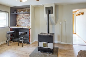 Ein Zimmer mit Kamin, einer Bar mit Hockern und Holzboden.