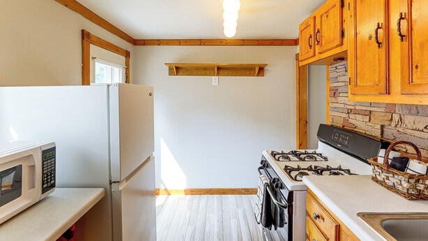 A kitchen with wooden cabinets, a white refrigerator, a stove, and a microwave. - Walk to Park & Creek! Spearfish Couple’s Retreat (Spearfish)