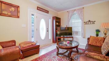 A living room with a television, leather sofas, a coffee table, and a decorative sign above the door.