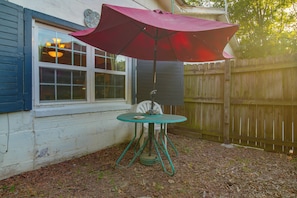 A patio area with a table and an umbrella, a wooden fence, and a house with a window. - 1 Mi to UAFS! Quiet & Cozy Apt w/ Fenced Yard (Fort Smith)