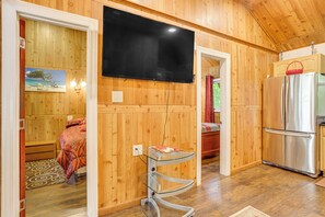 A wooden-paneled room with a flat-screen TV mounted on the wall, a stainless steel refrigerator, and a glass shelf unit. - 2-Unit Combo, 6 Mi to Bethel Woods Center! (Mongaup Valley)
