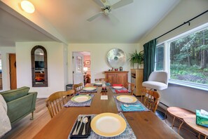 A dining area with a wooden table set for four, surrounded by chairs, a ceiling fan, and a large window with a view of trees. - Deck & Stunning Views! Family Getaway in Hamilton (Hamilton)