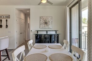 A dining area with a white table, four woven placemats, white chairs, a ceiling fan, and a wall-mounted artwork. - Relax Poolside, Explore South Mtn! Extended Escape (Phoenix)
