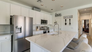 A modern kitchen with white cabinetry, stainless steel appliances, and a marble island. - Relax Poolside, Explore South Mtn! Extended Escape (Phoenix)