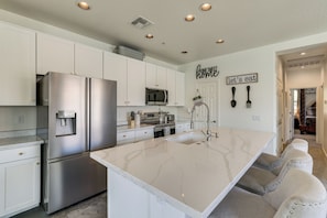 A modern kitchen with white cabinetry, stainless steel appliances, and a marble island. - Relax Poolside, Explore South Mtn! Extended Escape (Phoenix)