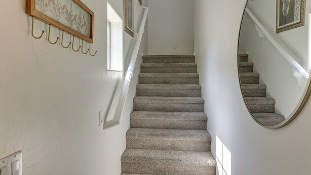 A staircase with carpeted steps, a wall-mounted mirror, and several framed pictures. - Relax Poolside, Explore South Mtn! Extended Escape (Phoenix)