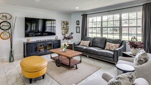 Ein Wohnzimmer mit Sofa, Hocker, Couchtisch und Fernseher.