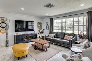 A living room with a sofa, ottoman, coffee table, and a television. - Mid-Term Stay in Sarasota! Home w/ Pool & Hot Tub (Sarasota)