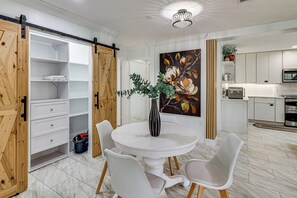 A modern kitchen with white cabinets, a dining area with a white table and chairs, and a sliding barn-style door leading to a storage area. - Mid-Term Stay in Sarasota! Home w/ Pool & Hot Tub (Sarasota)