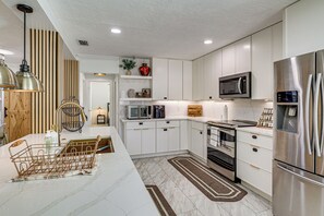 A modern kitchen with white cabinetry, stainless steel appliances, and a marble countertop. - Mid-Term Stay in Sarasota! Home w/ Pool & Hot Tub (Sarasota)