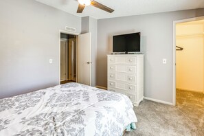 Un dormitorio con cama, cómoda, televisor y ventilador de techo.