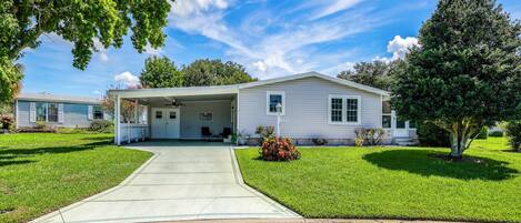 A single-story house with a covered porch, a front lawn, and a clear sky.