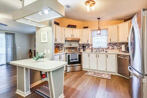 Una cocina moderna con armarios blancos, electrodomésticos de acero inoxidable y una isla central.
