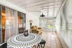 Una habitación iluminada por el sol, con una mesa estampada, un sofá y una lámpara.