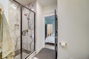 Een moderne badkamer met een douche in een glazen cabine, een handdoekrek en een zichtbare toiletpapierhouder.
